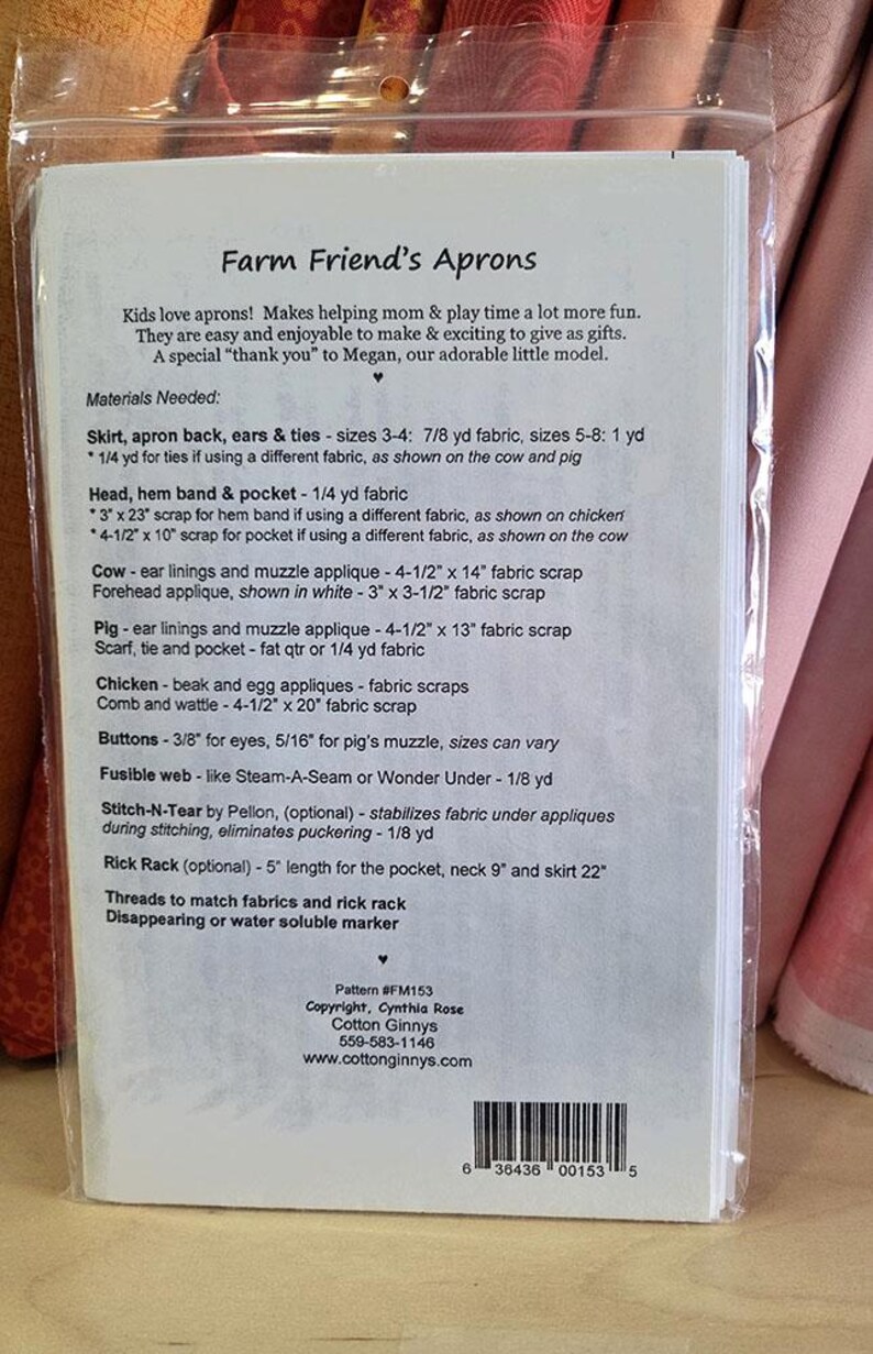 May include: A sewing pattern packet titled Farm Friend's Aprons, enclosed in a clear plastic sleeve. The white paper insert lists materials needed for children's aprons, including fabric yardage, buttons, and rick rack, with a barcode at the bottom.