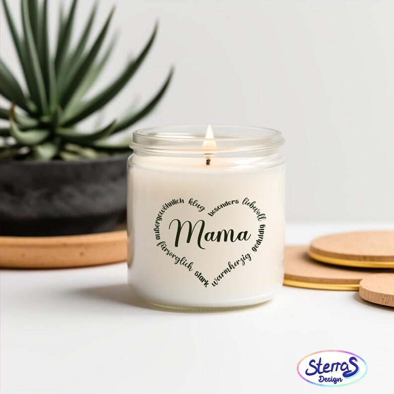 May include: A white candle in a glass jar with a black circle label that reads "Mama" surrounded by German words describing a mother. The words are "au&szlig;ergew&ouml;hnlich" (extraordinary), "klug" (smart), "besonders" (special), "liebvoll" (loving), "f&uuml;hrsorglich" (caring), "stark" (strong), "warmherzig" (warm-hearted), "geliebt" (loved).