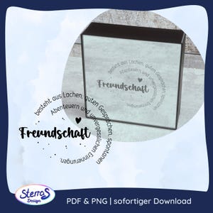 Puede incluir: Una caja cuadrada con un panel frontal texturizado en azul claro que presenta el texto en alemán Freundschaft besteht aus Lachen, guten Gesprächen, Abenteuern und unvergesslichen, spontanen Erinnerungen, dispuesto en un patrón circular con corazones.