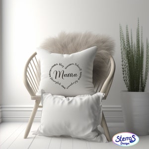 May include: White throw pillow with black text that reads "Mama" surrounded by a circle of German words. The pillow is sitting on a white wicker chair.