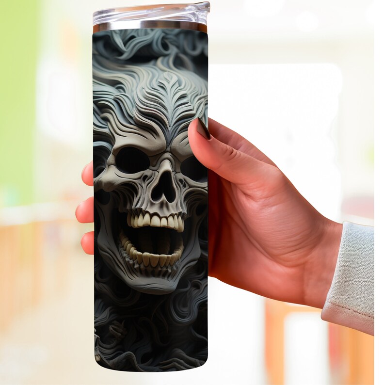 K&ouml;nnte beinhalten: Ein Edelstahlbecher mit einem schwarzen und wei&szlig;en Totenkopf-Motiv. Der Totenkopf ist von wirbelnden, rauch&auml;hnlichen Mustern umgeben.