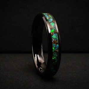 Może przedstawiać: Czarny pierścionek z węglika wolframu z zielono-niebieską opaleną inkrustacją.