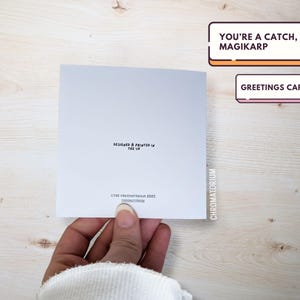 May include: A white greeting card with the text "You're a catch, Magikarp" in black lettering. The card also includes the text "Greetings Card" in black lettering.