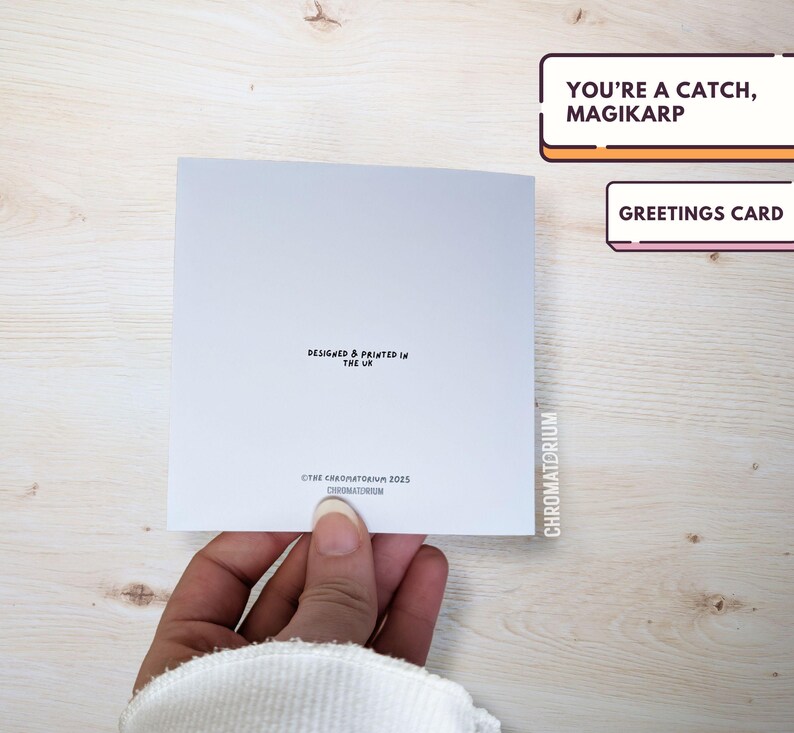 May include: A white greeting card with the text "You're a catch, Magikarp" in black lettering. The card also includes the text "Greetings Card" in black lettering.