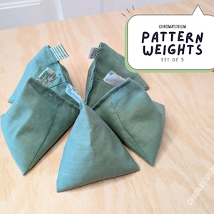 May include: Set of five green fabric triangular weights with a white and green patterned design. The weights are labelled "Chromatorium Pattern Weights Set of 5".
