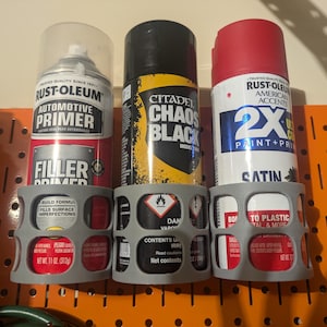 May include: Three spray paint cans in gray holders. The cans are Rust-Oleum Automotive Primer, Citadel Chaos Black, and Rust-Oleum 2X Ultra Cover Satin.