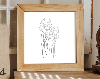 May include: A black and white line drawing of daffodils in a wooden frame. The drawing is on white paper and the frame is a light brown wood.