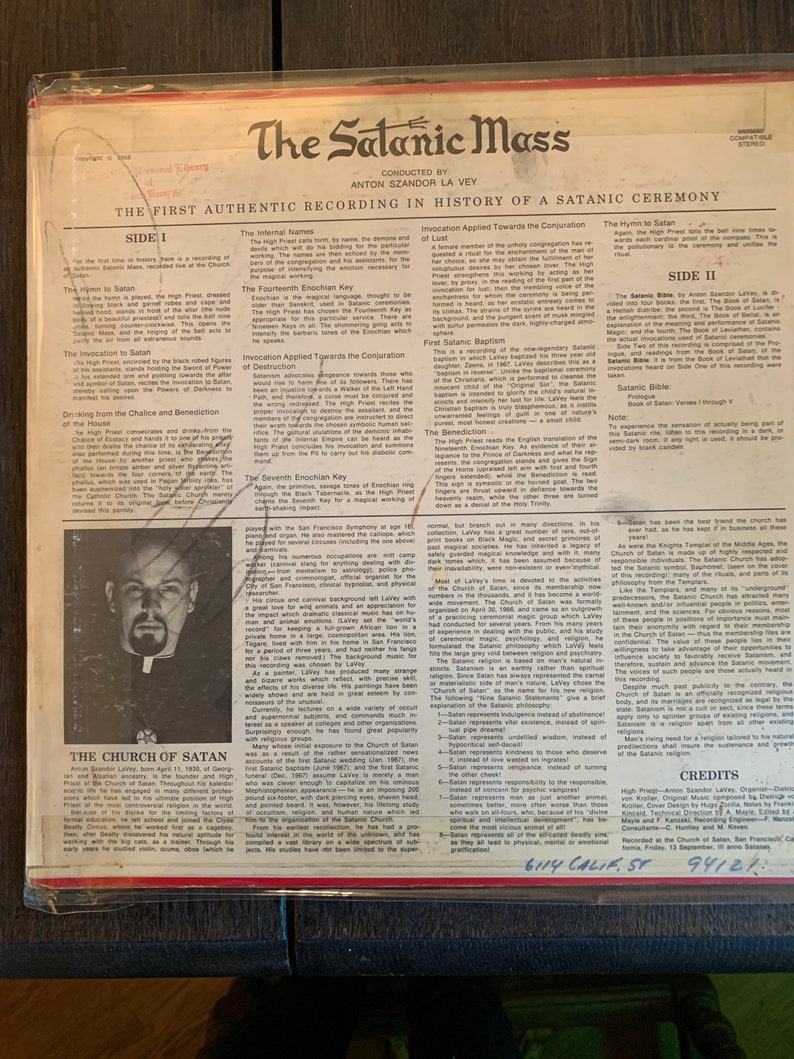 May include: A black and white photo of Anton Szandor LaVey, the founder of the Church of Satan, on the cover of a vinyl record titled "The Satanic Mass". The record cover includes text describing the contents of the record, including the "Hymn to Satan", "Invocation to Satan", and "The Satanic Bible".