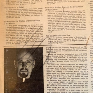 May include: A black and white photo of Anton Szandor LaVey, the founder of the Church of Satan. The photo shows LaVey's face and a portion of his clerical collar. The text "The Church of Satan" is printed in bold, white letters on a black background below the photo. The text "Anton Szandor LaVey, born April 11, 1930, of Georgian and Alsatian ancestry, is the founder and High Priest of the Church of Satan. Throughout his kaleidoscopic life, he has been a musician, a writer, a lecturer, a painter, a photographer, a hypnotist, a criminologist, a police photographer, a circus performer, a carnival worker, and a researcher.  He has also been a musician, a writer, a lecturer, a painter, a photographer, a hypnotist, a criminologist, a police photographer, a circus performer, a carnival worker, and a researcher." is printed below the title.