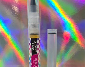 Puede incluir: Un bolígrafo de aceite para cutículas de plástico transparente con punta de pincel negra y tapa base negra. La etiqueta presenta un patrón de cuadros colorido y el texto "CHECKERED Finish CUTICLE OIL 6ml .2oz". Una tapa transparente está al lado.