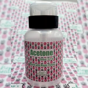 Puede incluir: Una botella de plástico transparente con tapa negra y una etiqueta que dice "Acetone 200ml / 6.7 oz Mezclado con Magic Potion Lizmo's Creations" con un patrón de piña.