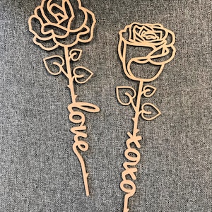 May include: Two wooden rose cutouts with the words "love" and "forever" written on the stems.