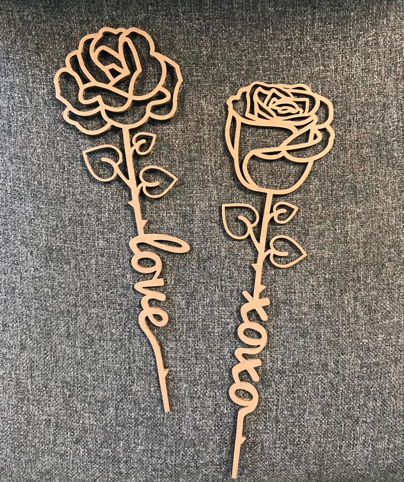 May include: Two wooden rose cutouts with the words "love" and "forever" written on the stems.
