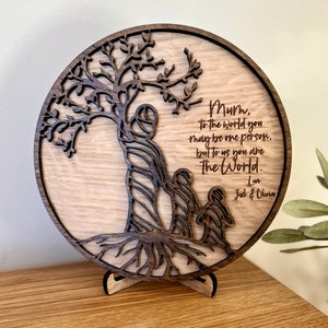 May include: A wooden circle with a carved tree design and the words "Mum, to the world you may be one person, but to us you are the world. Love Jack & Olivia" engraved on it.