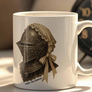 May include: White ceramic mug featuring a detailed illustration of a medieval helmet with a lace-trimmed hood and bow. The mug is set on a white surface, with two vintage alarm clocks in the background.