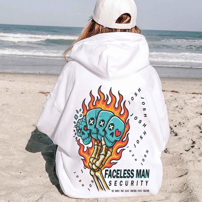 Puede incluir: Sudadera con capucha blanca con un dise&ntilde;o gr&aacute;fico en la espalda. El dise&ntilde;o presenta tres calaveras azules con detalles de cruz y coraz&oacute;n, rodeadas de llamas y una mano esquel&eacute;tica. El texto dice "FACELESS MAN SECURITY".