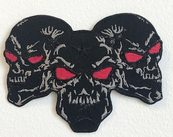 Parche bordado para planchar con tres calaveras negras y ojos ardientes