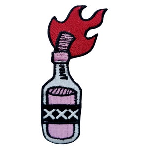 Könnte beinhalten: Eine rosa und weiße Glasflasche mit einer roten Flamme oben. Die Flasche hat ein schwarzes Band mit den Buchstaben "XXX" darauf.