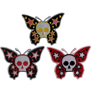 May include: Three embroidered iron-on patches featuring a skull and crossbones design inside a butterfly shape. The butterflies are black with pink stars, red with white stars, and black with white stars.