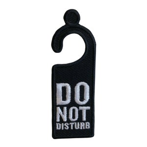 May include: Black door hanger with a white "Do Not Disturb" message. The hanger has a hook at the top.