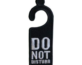 Peut inclure: Un porte-nom en noir avec un message "Ne pas déranger" en blanc. Le porte-nom a un crochet en haut.