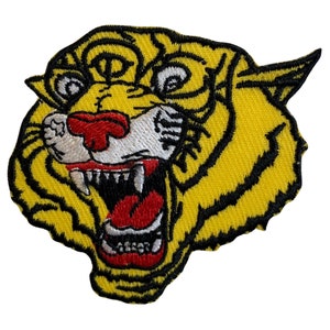 May include: A yellow embroidered tiger head patch with black outlines and red and white details. The tiger's mouth is open, showing sharp teeth.