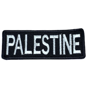 May include: Black embroidered patch with white lettering that reads "PALESTINE".