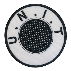 Könnte beinhalten: Runder weißer gestickter Aufnäher mit schwarzen Nähten. Der Aufnäher zeigt einen schwarzen Kreis mit einem Gittermuster in der Mitte und den Buchstaben "N.I.T." um den Kreis herum.
