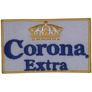 Peut inclure: Un écusson brodé blanc avec un contour doré. L'écusson présente une couronne dorée et le texte "Corona Extra" en bleu.