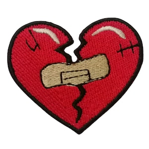 May include: A red heart-shaped patch with a black outline, broken in two and held together with a beige bandage. The heart is stitched with black thread.