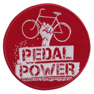 Könnte beinhalten: Roter gestickter Aufnäher mit einem weißen Fahrrad und einer erhobenen Faust. Der Text "PEDAL POWER" befindet sich unter dem Fahrrad.
