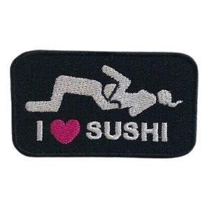 Può includere: Toppa ricamata nera con una silhouette bianca di una coppia in una posa suggestiva e il testo "I love SUSHI" con un cuore rosa.