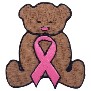 Peut inclure: Ours en peluche brun tenant un ruban rose. Le ruban est noué en un nœud autour du cou de l'ours.