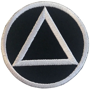 Puede incluir: Triángulo blanco bordado dentro de un círculo blanco sobre fondo negro.