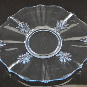 May include: A light blue glass serving plate with a scalloped edge and decorative floral designs. The plate has four handles.