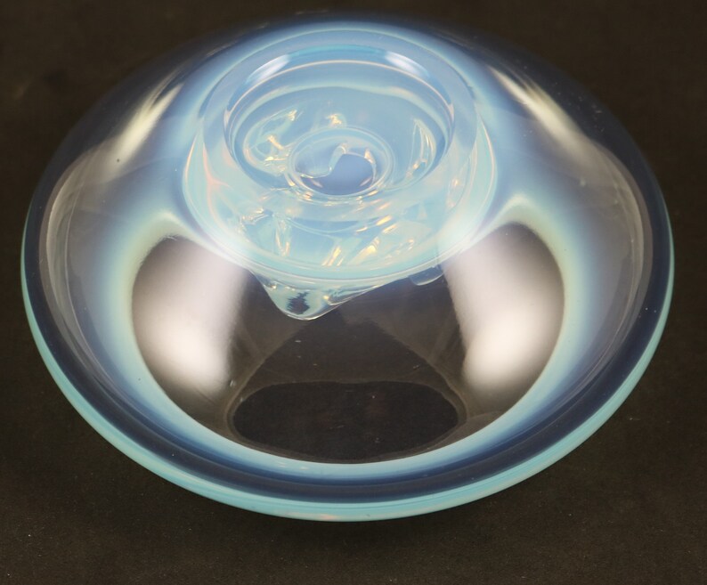 May include: A light blue glass bowl with a swirling, opaque white design in the center. The bowl has a smooth, rounded rim and a slightly flared base.