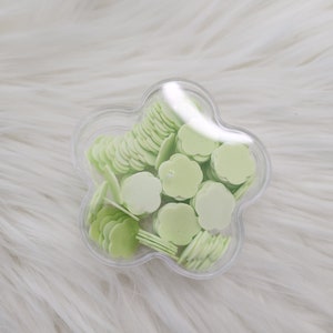 May include: A clear plastic flower-shaped container filled with light green flower-shaped confetti.
