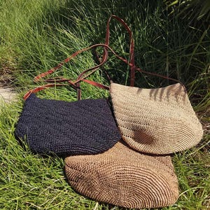 May include: Three straw tote bags with leather straps. One bag is black, one is light brown, and one is a darker brown.