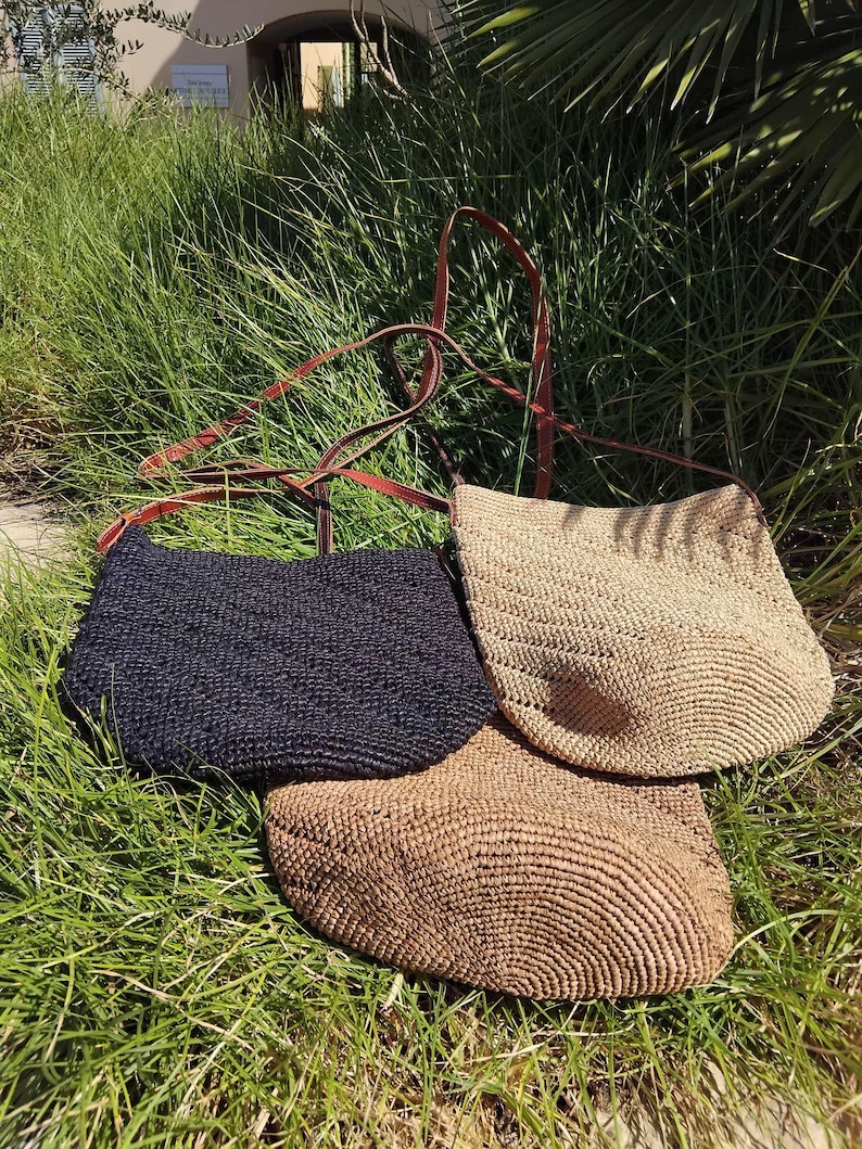 May include: Three straw tote bags with leather straps. One bag is black, one is light brown, and one is a darker brown.