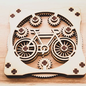 May include: A wooden model of a bicycle with gears, the wheels are made of wood and have a brown cross pattern in the center. The bicycle is surrounded by smaller gears.
