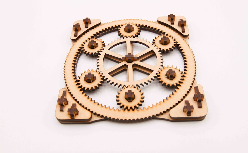 May include: A wooden gear set with eight interlocking gears, all connected to a central hub. The gears are made of light brown wood with dark brown accents.