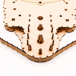 May include: A laser-cut wooden puzzle, featuring a complex design with multiple interlocking pieces. The puzzle has a light brown color and is made of thin wooden sheets. The design includes various shapes and patterns, with a focus on precision and detail.