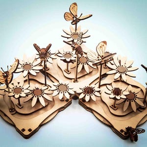 Può includere: Una scultura floreale in legno con piattaforme a strati, margherite e farfalle tagliate al laser. La scultura ha una finitura in legno naturale ed è adornata da dettagliate figure di farfalle e api, creando una scena di giardino stravagante.