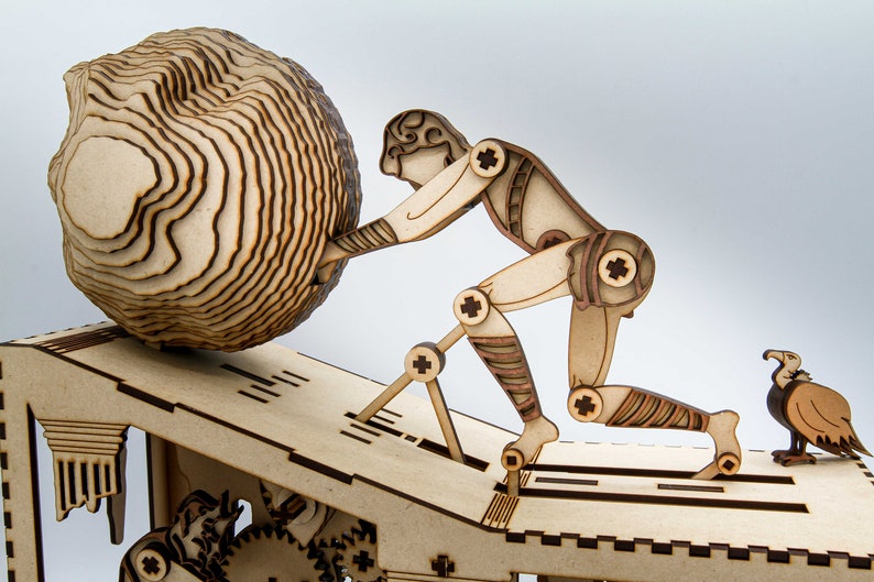 May include: A wooden model of a figure pushing a large, round object up a ramp. The figure is made of layered wood and has articulated joints. A small wooden bird is perched on the ramp.