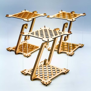 Peut inclure: Trois structures de tenségrité en bois clair dotées de plateformes carrées aux motifs découpés au laser. Chaque unité se compose d'un carré supérieur et inférieur reliés par de fines cordes blanches, créant un effet flottant avec un support central.