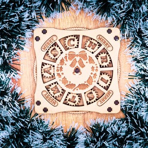 May include: A wooden Christmas puzzle with the words "MERRY CHRISTMAS" arranged around a central wreath design. The puzzle is surrounded by green and white tinsel, creating a festive holiday scene.
