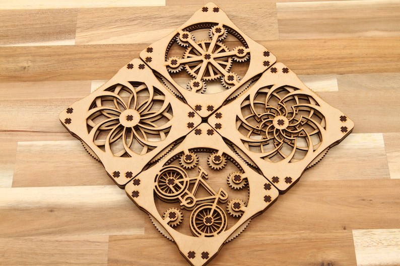May include: Four wooden coasters with intricate laser-cut designs. Each coaster features a different geometric pattern, including a bicycle, a spiral, and two variations of a flower.