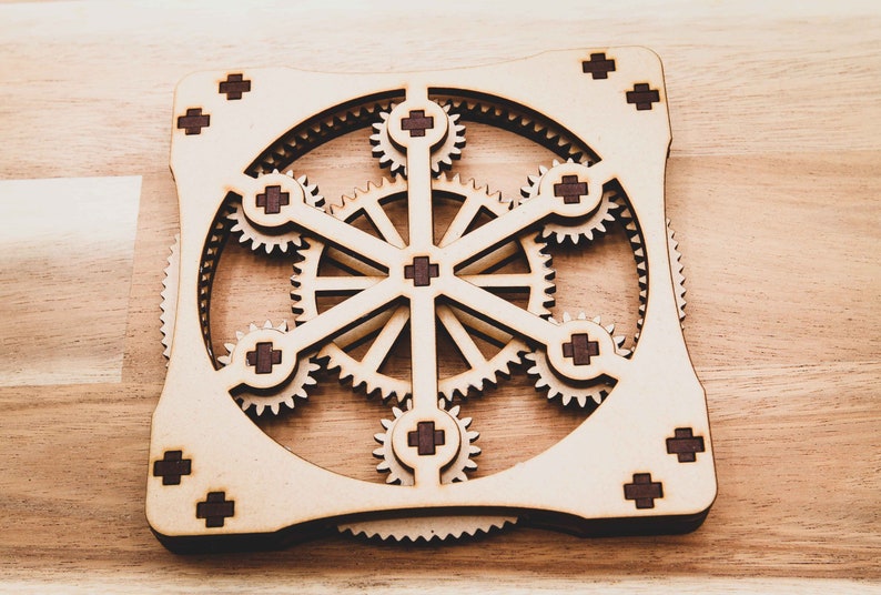 May include: A wooden gear puzzle with a square frame and multiple interlocking gears. The gears are made of light brown wood and have dark brown accents.