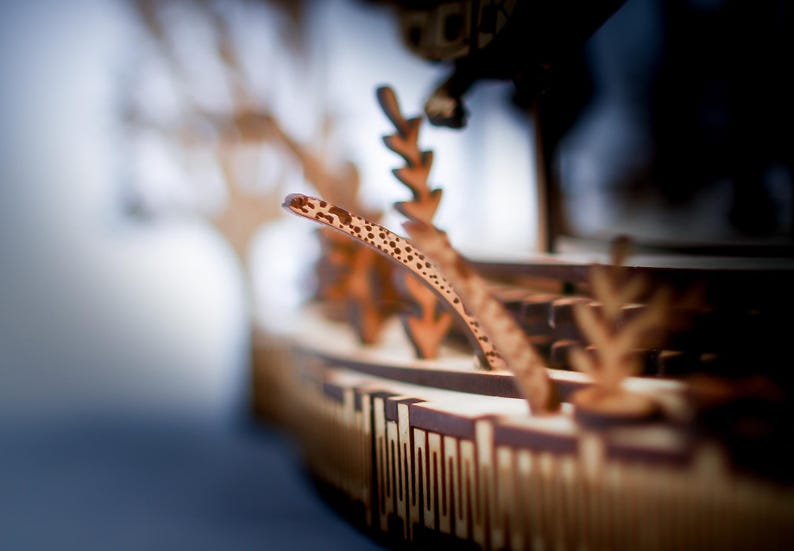 May include: A detailed wooden model of a ship, featuring intricate cut-out designs and a curved, patterned element. The model is primarily brown with lighter accents, showcasing a focus on craftsmanship and detail.