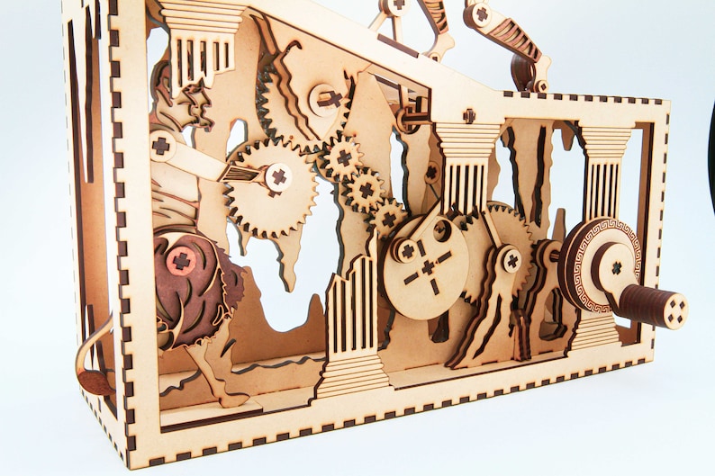 May include: A wooden kinetic sculpture with intricate gears and a hand crank. The sculpture features a stylized figure riding a horse, surrounded by columns and other architectural elements.